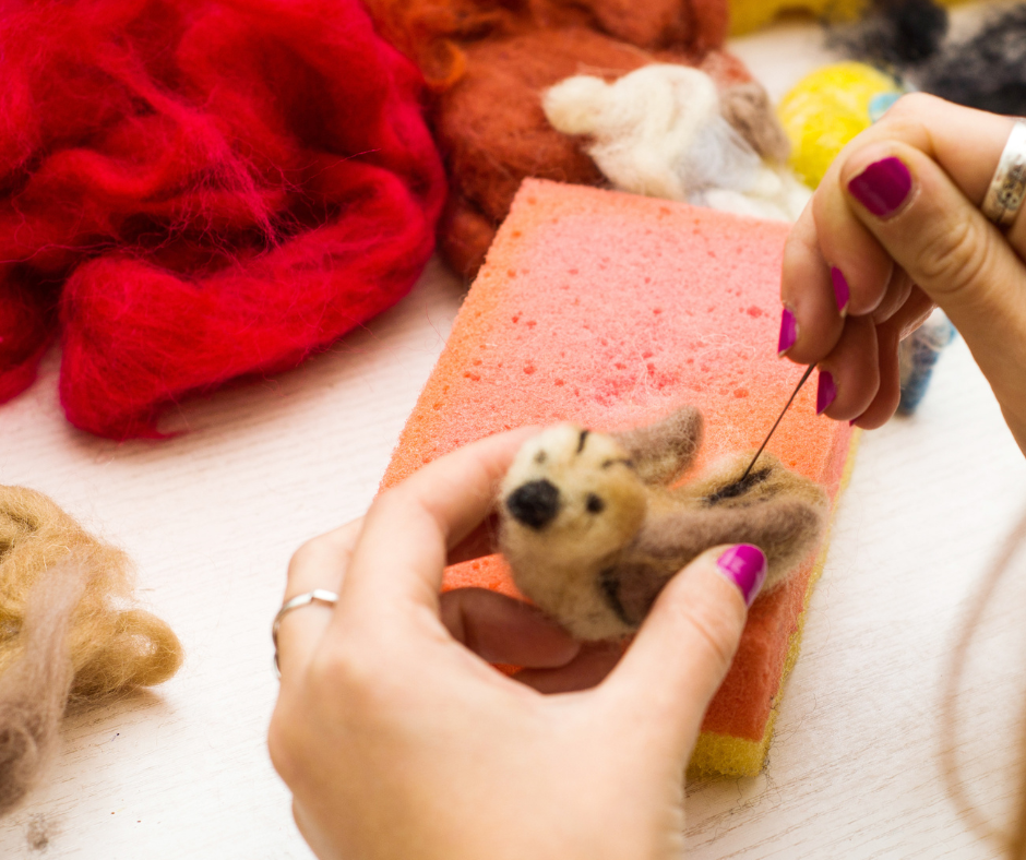 na zdjęciu jest zabawka z filcu i ręce kobiety, która filcuje